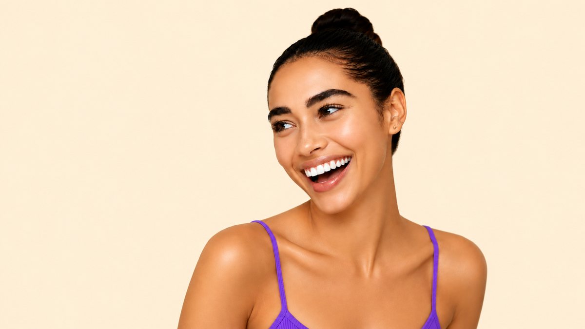 A woman smiling brightly, hair in a bun